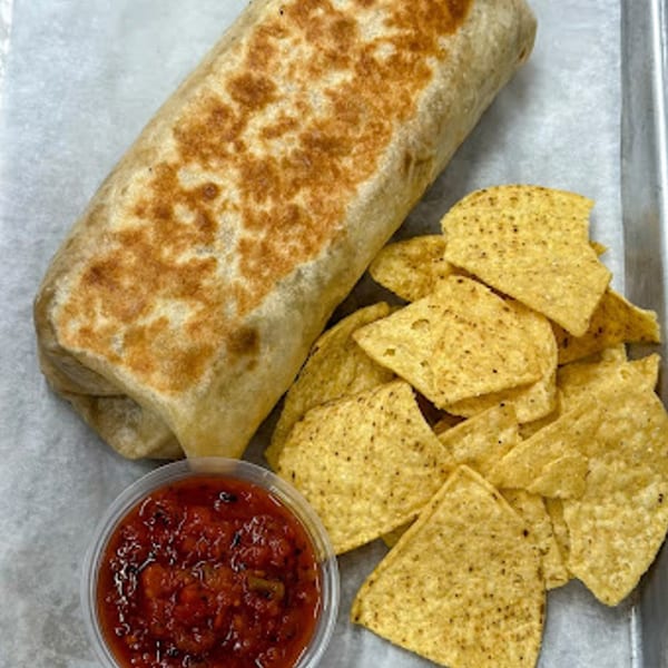 A large grilled burrito, a pile of tortilla chips, and a cup of salsa on a tray.