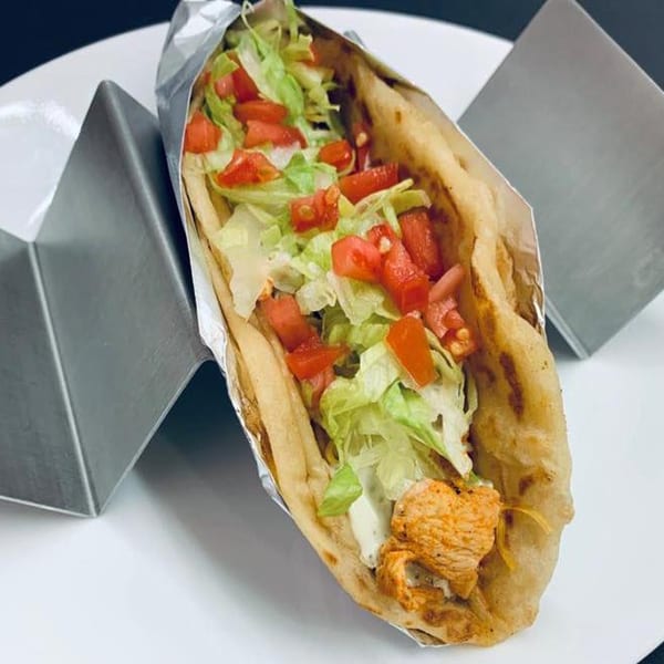 A Marabella's Tacos chicken taco with lettuce and tomatoes in a foil-lined tortilla.